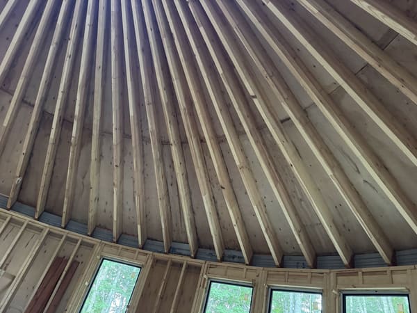 Looking up from the floor at the rafters fanning out over the sheathing, the wall head and the windows below