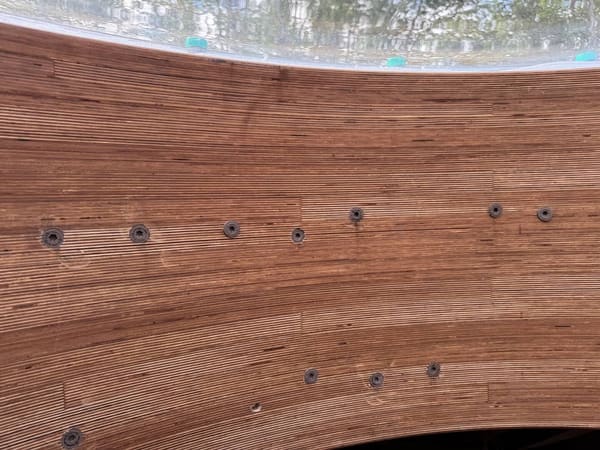 The laminated compression ring with two rows of fasteners, the acrylic dome edge and its teal setting blocks above