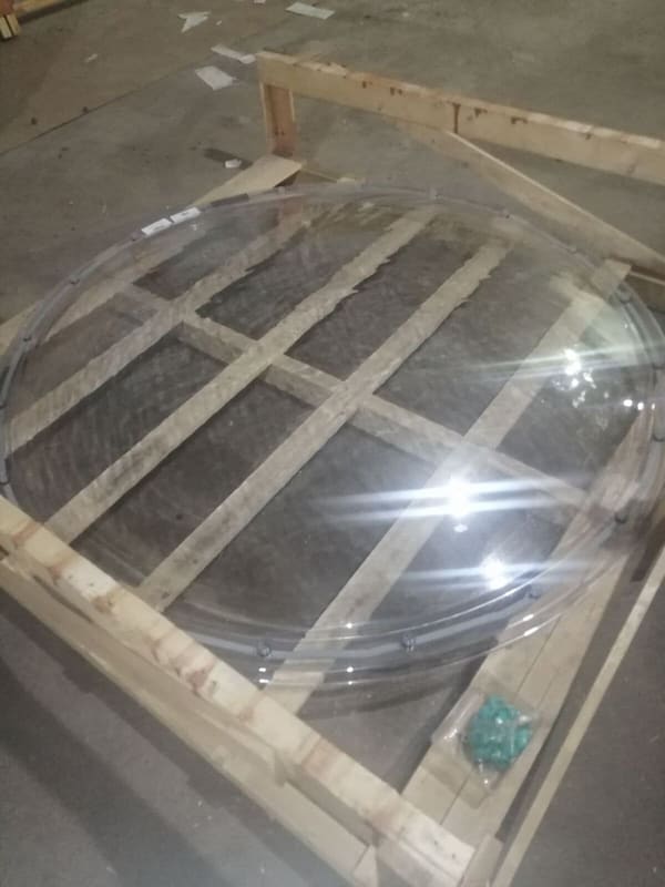 A clear acrylic dome lying in a timber crate with a bag of teal setting blocks beside it