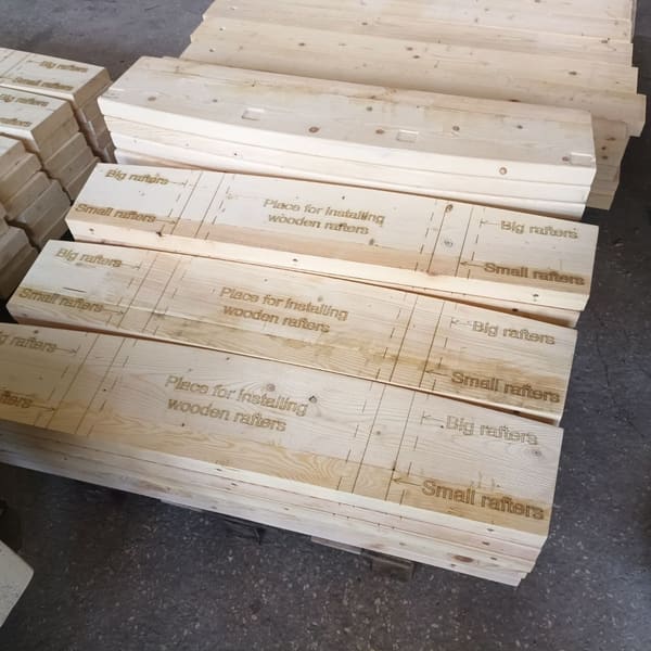 Glulam ring segments on a pallet, laser-engraved with the rafter positions