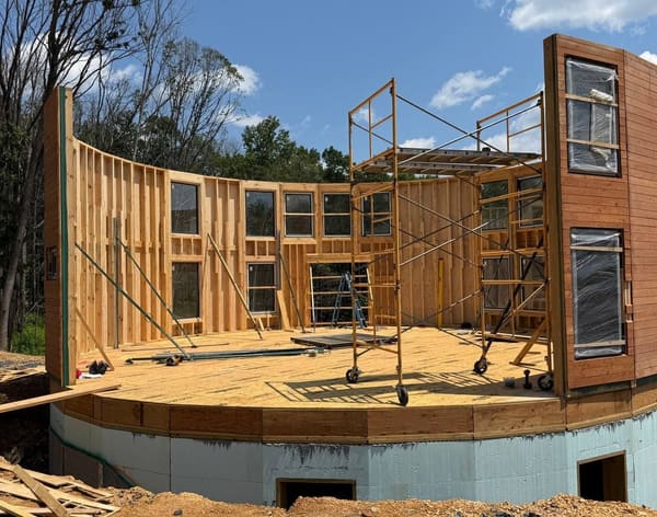 Two thirds of the wall ring standing on the deck, bare framed panels on the left and clad glazed panels on the right, props and a scaffold