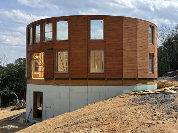 The complete wood-clad wall ring with windows standing on the insulated concrete basement walls